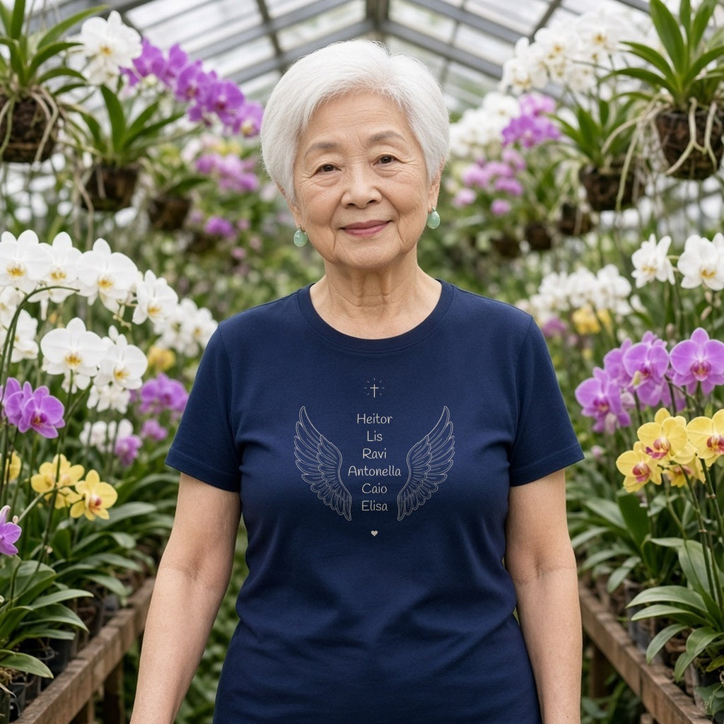 Avó de cabelo branco curto em uma estufa de orquídeas vestindo a camiseta de algodão peruano Os Anjos da Vovó azul-marinho com asas de anjo e os nomes de 6 netos