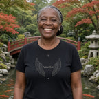 Avó de tranças grisalhas presas em um jardim japonês vestindo a camiseta de algodão peruano Os Anjos da Vovó preta com asas de anjo e o nome de 1 neto